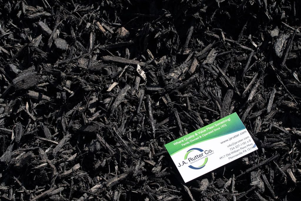 Green and white business card of J.A. Rutter Co. on top of Black Mulch