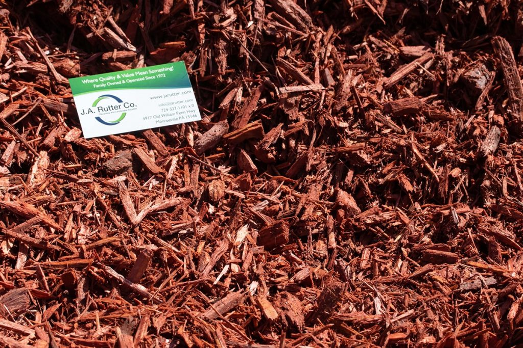 Green and white business card of J.A. Rutter Co. on top of Red Mulch